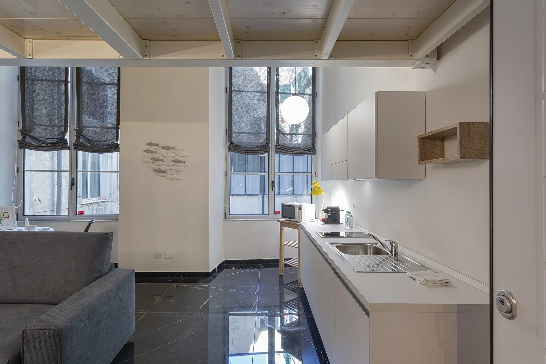 Una cocina luminosa con una encimera larga junto a grandes ventanas y una zona de estar.