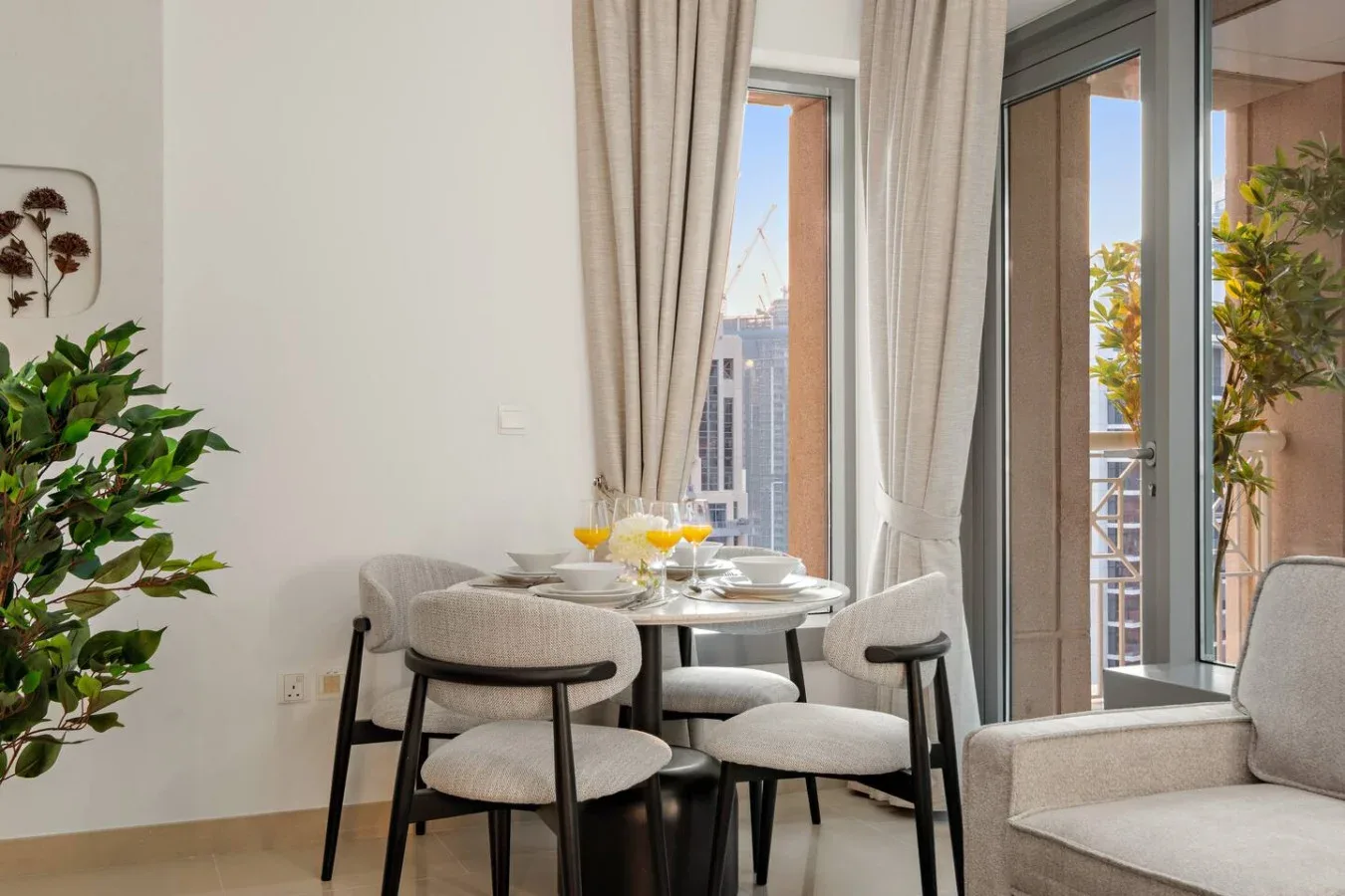 Un comedor luminoso con asientos alrededor de una mesa junto a ventanas altas y un balcón.