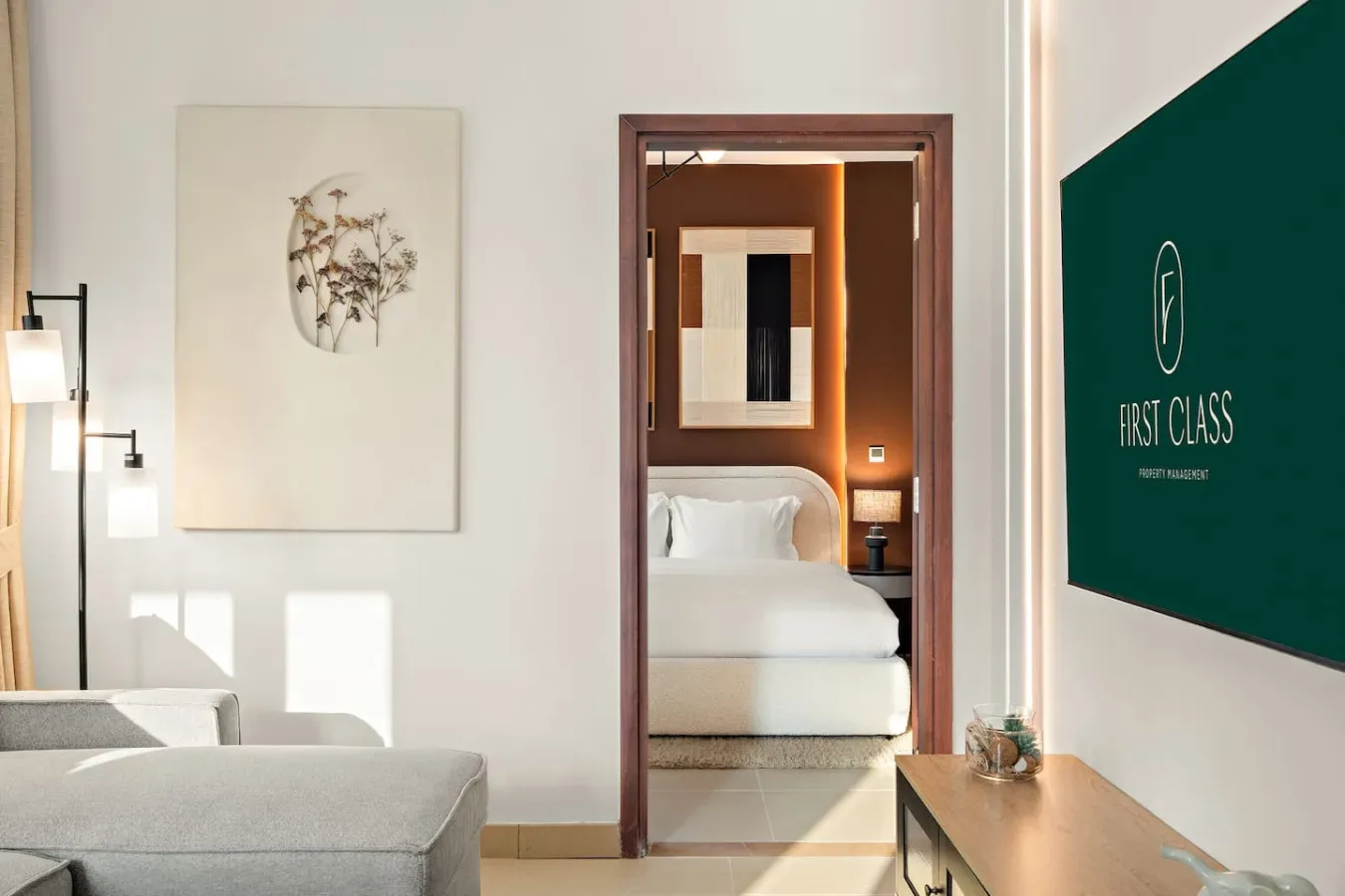 Una sala de estar se abre a un dormitorio, con asientos y una cama a la vista.