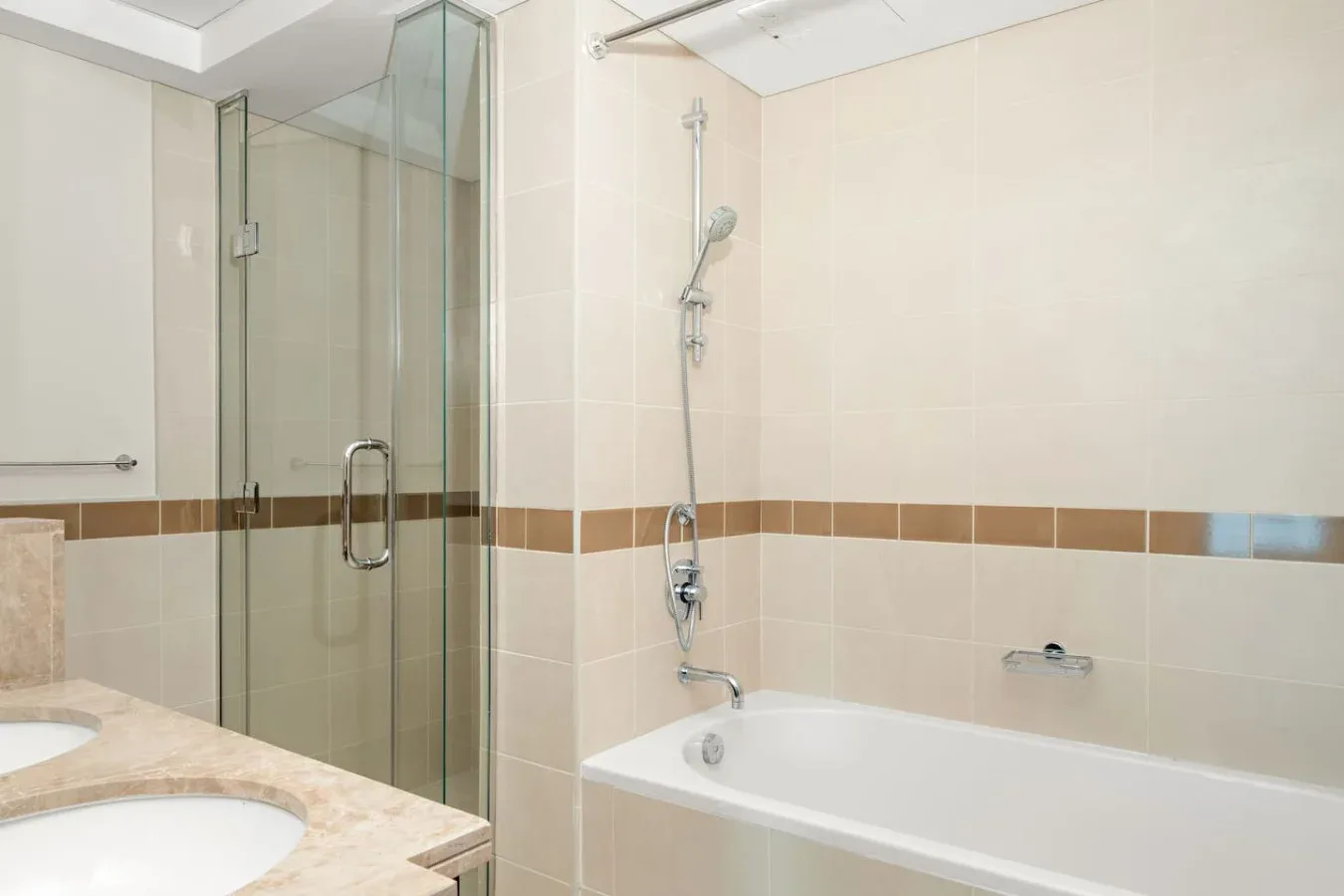 Un baño de azulejos con ducha de vidrio y bañera.