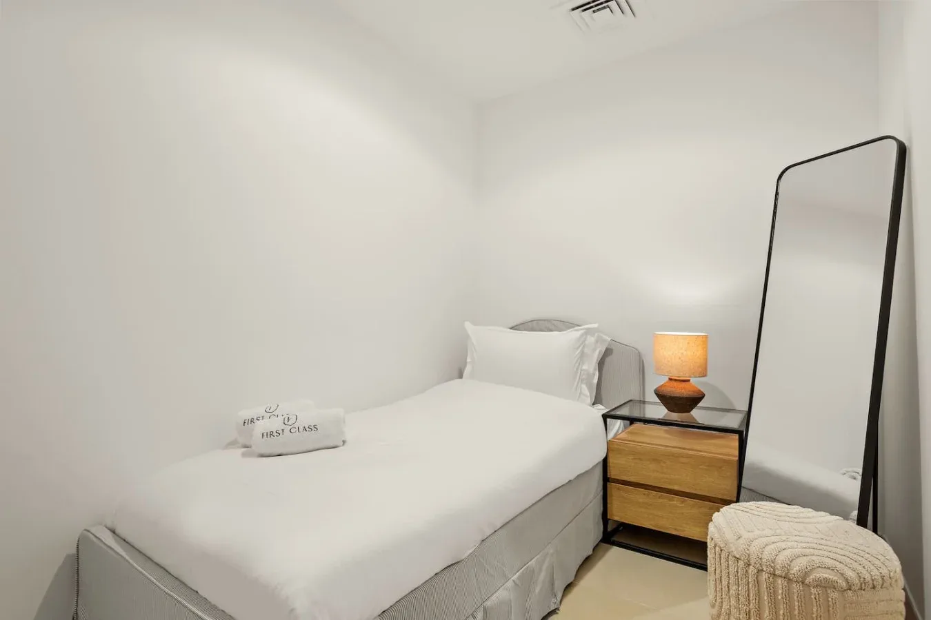 Un dormitorio luminoso con una cama tendida y una mesita de noche.