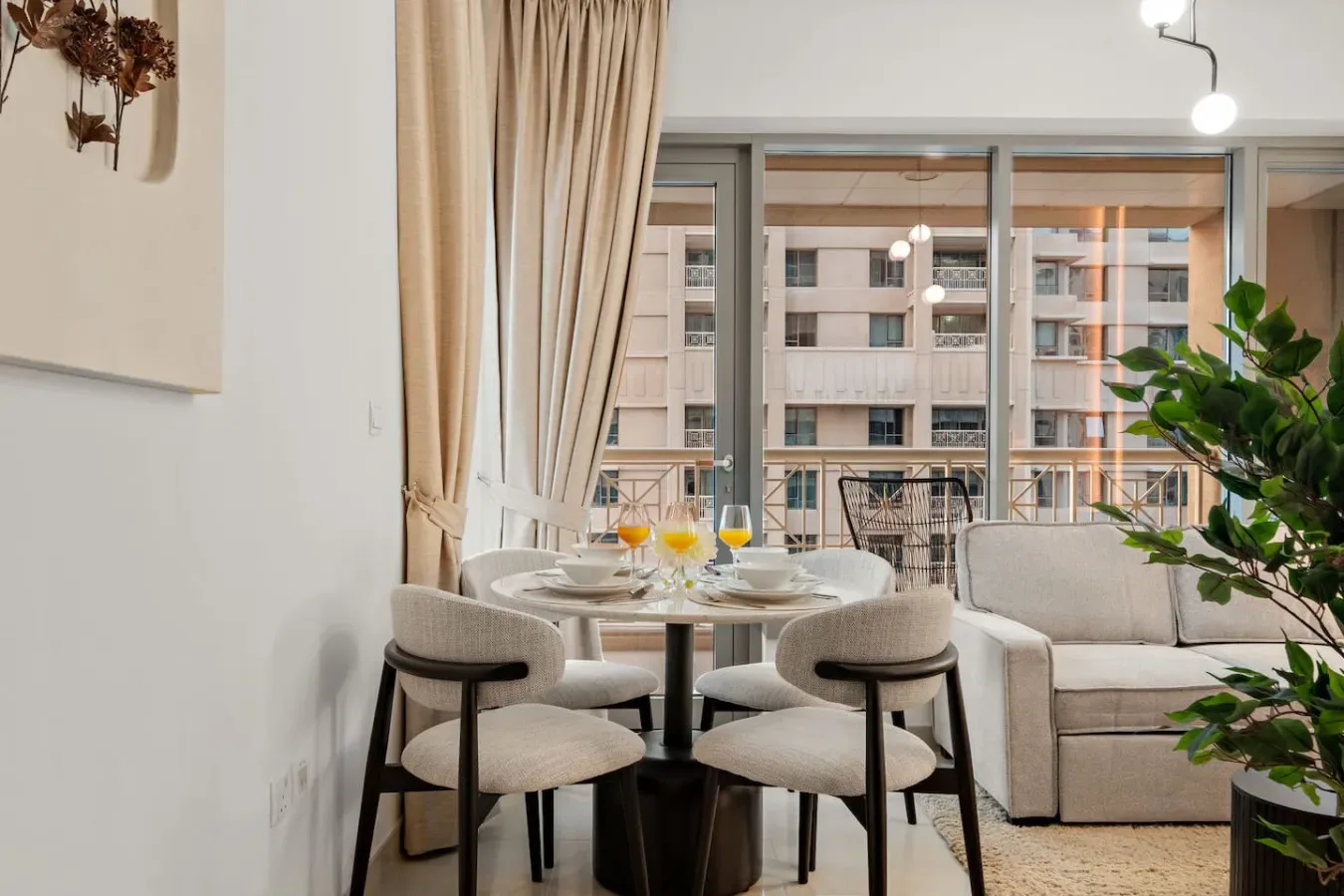 Comedor con una mesa redonda y grandes ventanales con edificios cercanos a la vista.