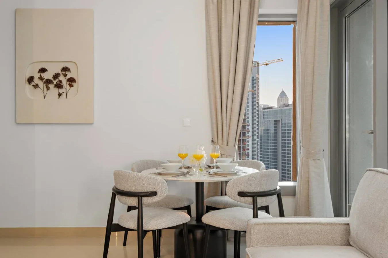 Comedor con una mesa redonda junto a una ventana con vistas a edificios de la ciudad.