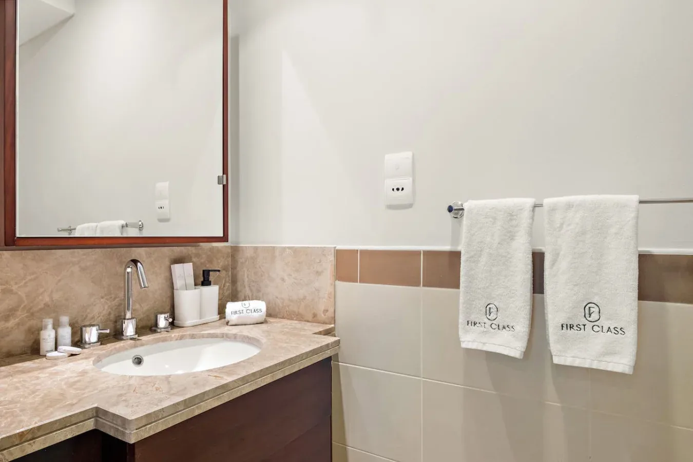 Un lavabo de baño con espejo y toallas colgadas en la pared.