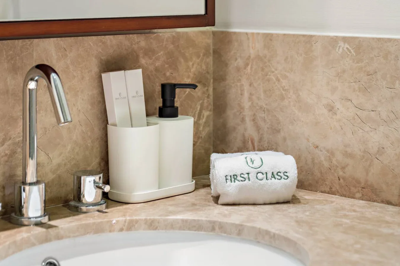 Un lavabo de baño con grifo cromado, artículos de aseo y una toalla doblada.