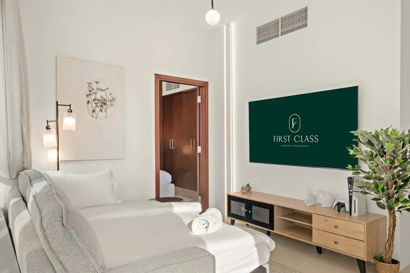 Un dormitorio luminoso con una cama, lámparas de noche y un televisor sobre un mueble bajo.