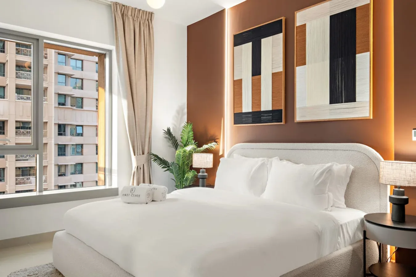 Un dormitorio luminoso con una cama blanca junto a una ventana grande.