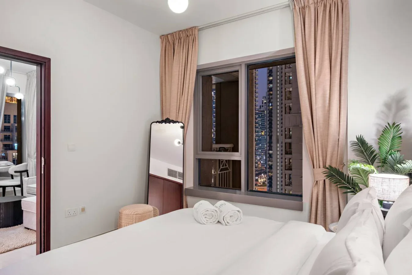 Un dormitorio con una cama junto a una ventana con cortinas y edificios a la vista.