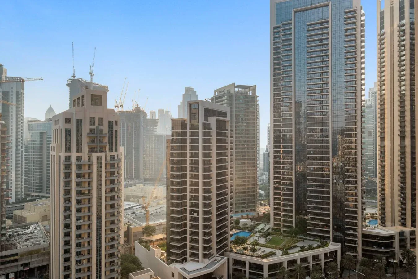 Un horizonte urbano de edificios altos y grúas de construcción bajo un cielo despejado.