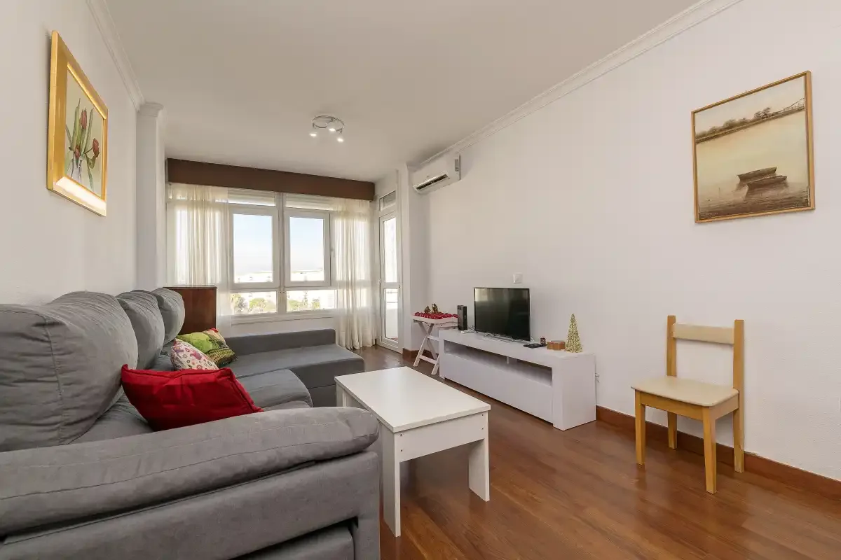 A living room with seating, a television, and windows.