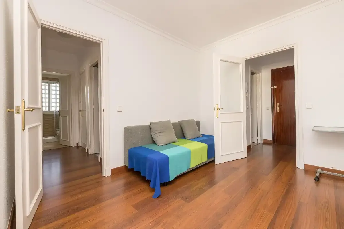 A bright room with a small seating area and wooden flooring.
