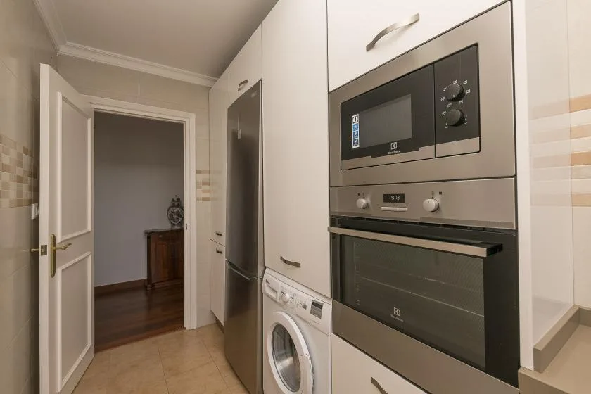 A compact kitchen with built-in appliances and a washing machine.