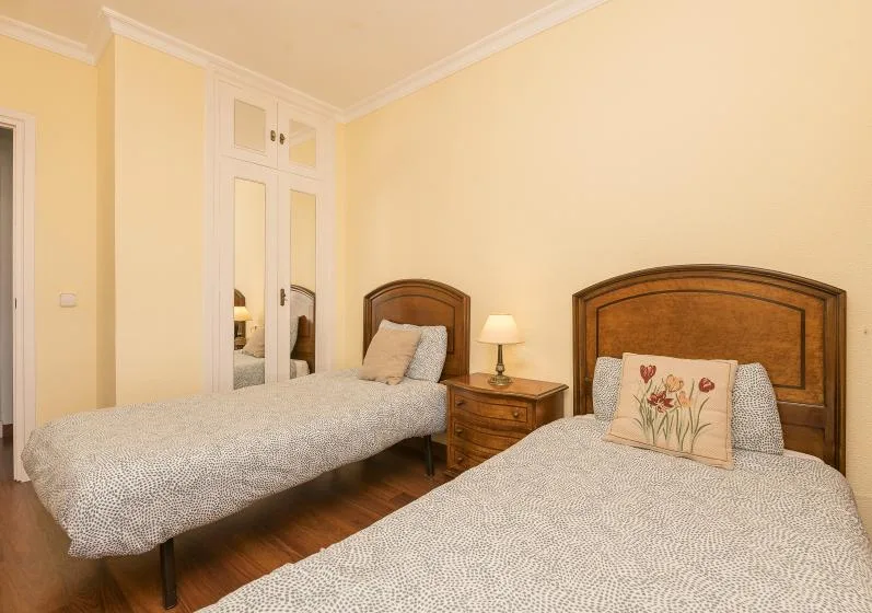 A bedroom with two beds and a small bedside table between them.