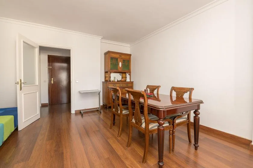 A dining area with a wooden table and chairs beside a glass-front cabinet.