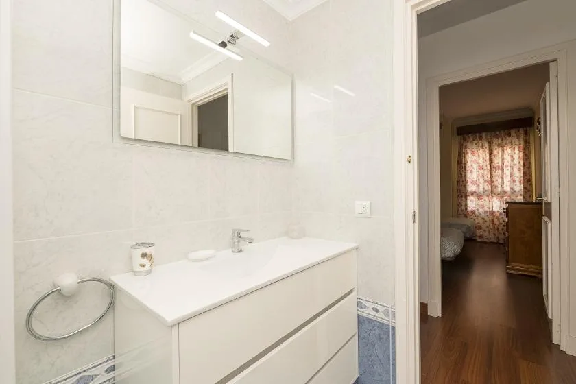 A bright bathroom with a wide sink and a large mirror.