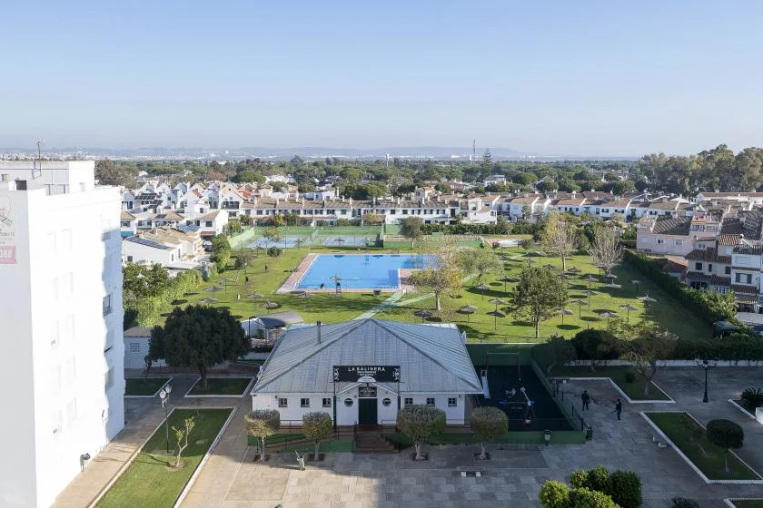 A landscaped outdoor area with a blue swimming pool and a low building in front.