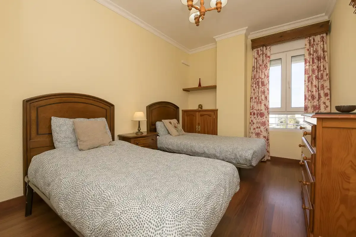 A bedroom with two beds and a window overlooking the outdoors.