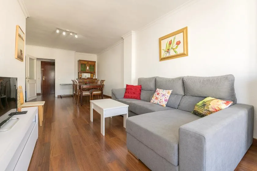 Living room with gray seating, a white coffee table, and a dining area beyond.