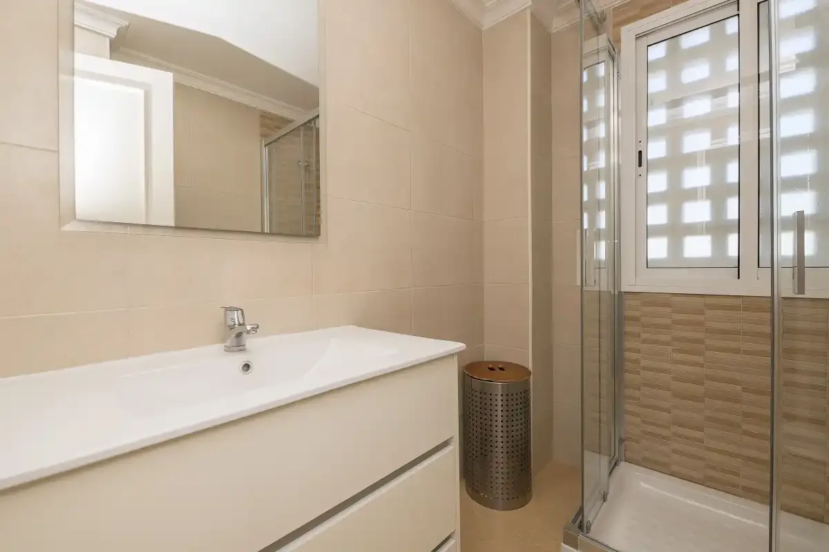 A bathroom with a sink, mirror, and shower.