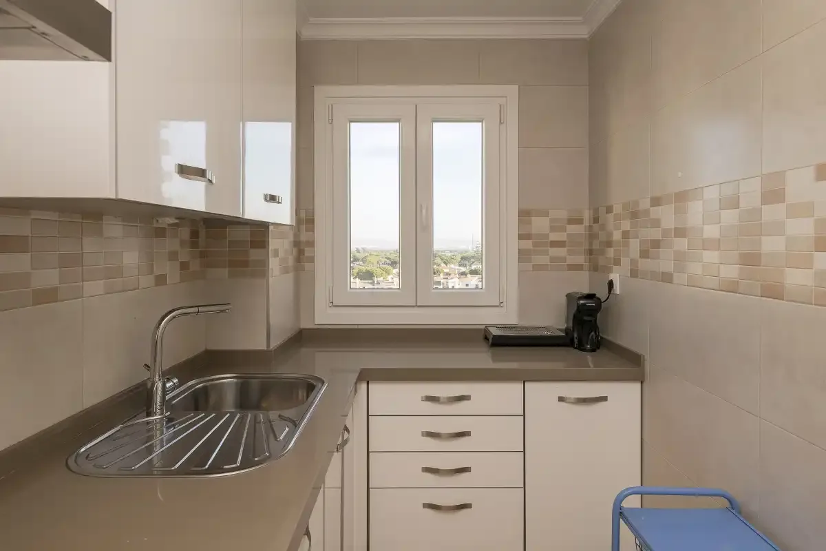 A tiled kitchen with a sink, countertop, and window.