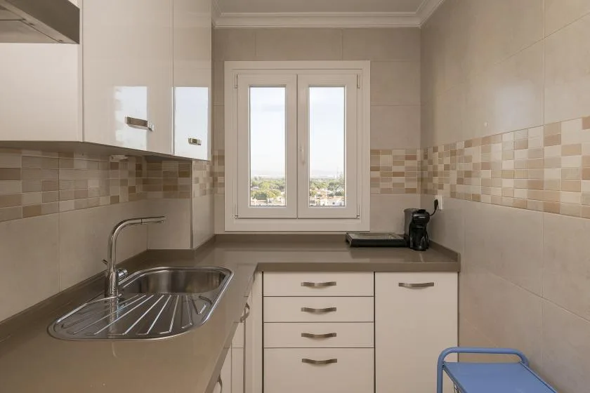 A tiled kitchen with a stainless-steel sink and a window above the counter.