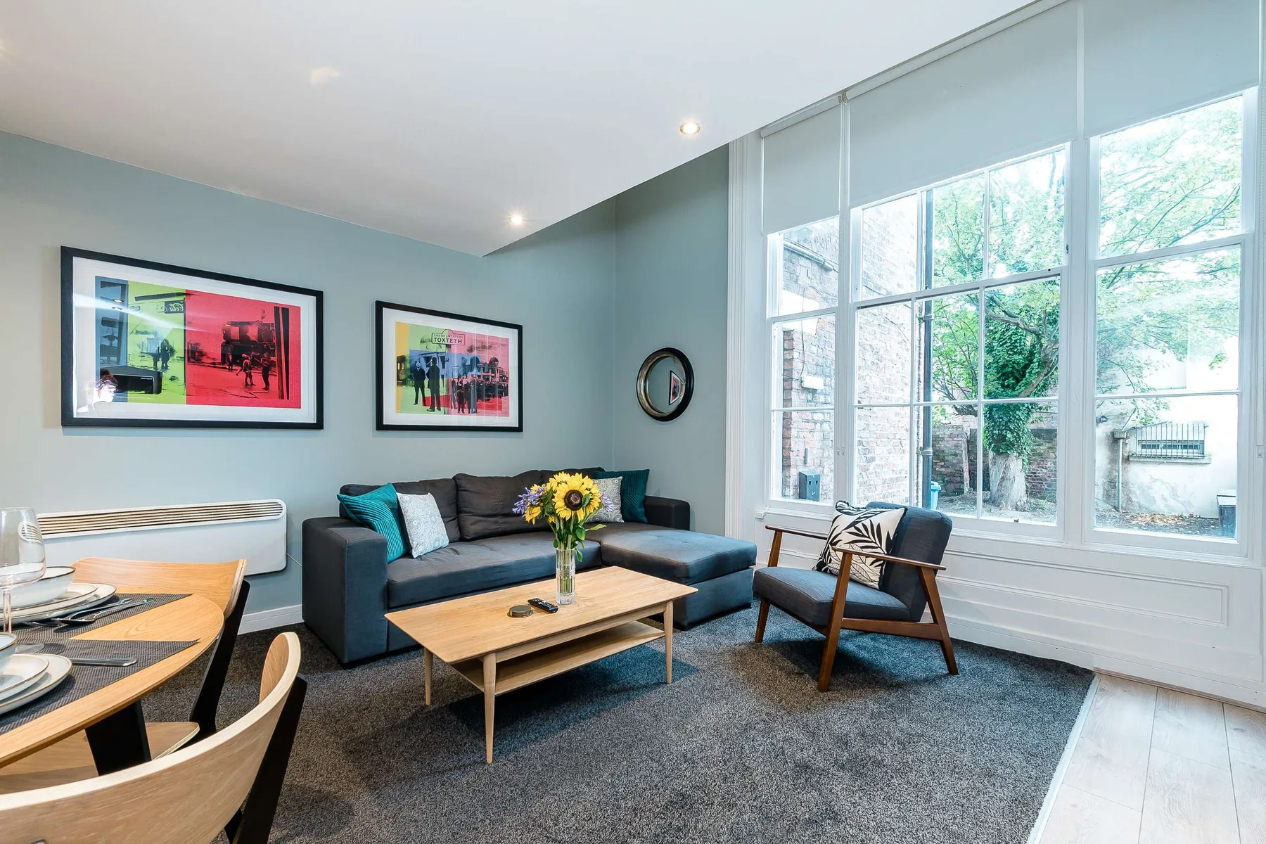 A bright living room with seating, a coffee table, and large windows.