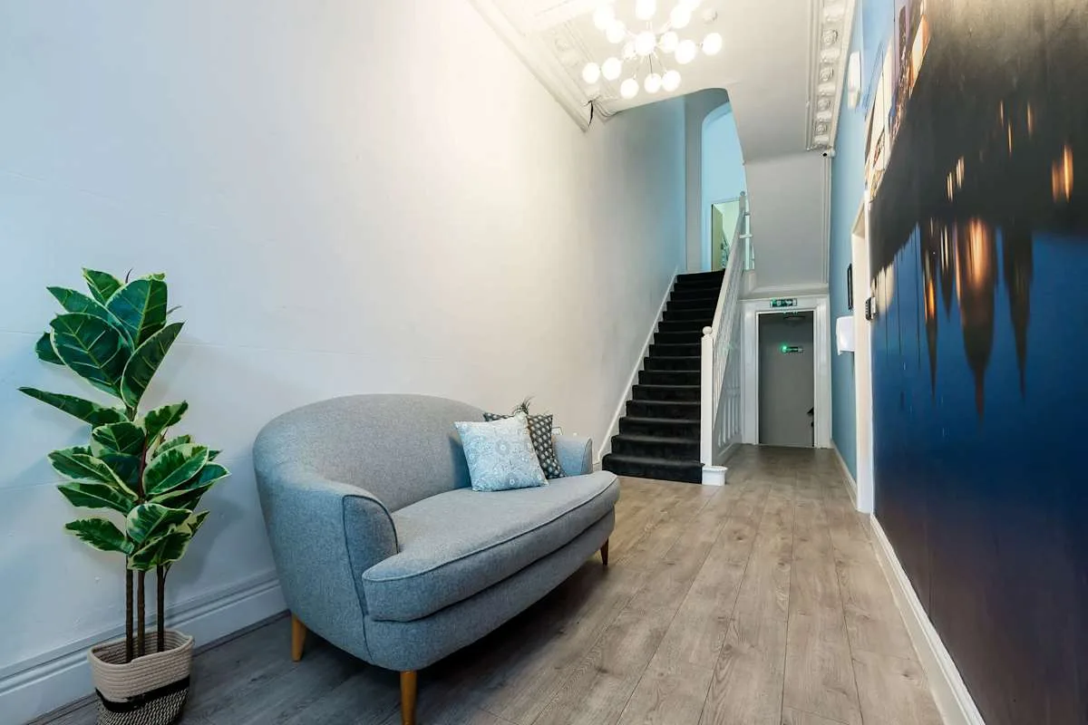A narrow hallway with a staircase and a small seating area.