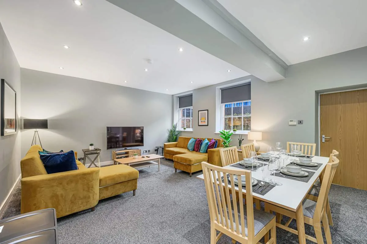 A living and dining room with seating, a television, and a set dining table.