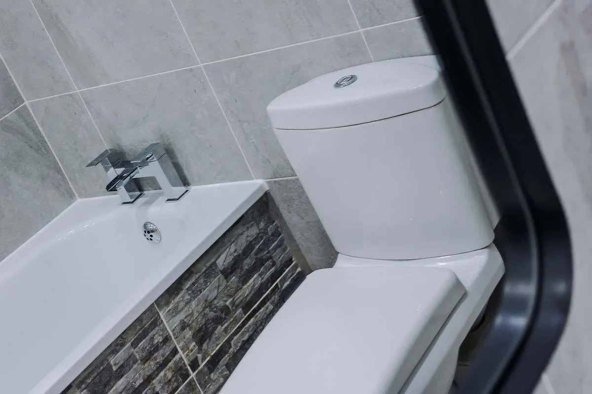 A bathroom with a toilet beside a tiled sink.