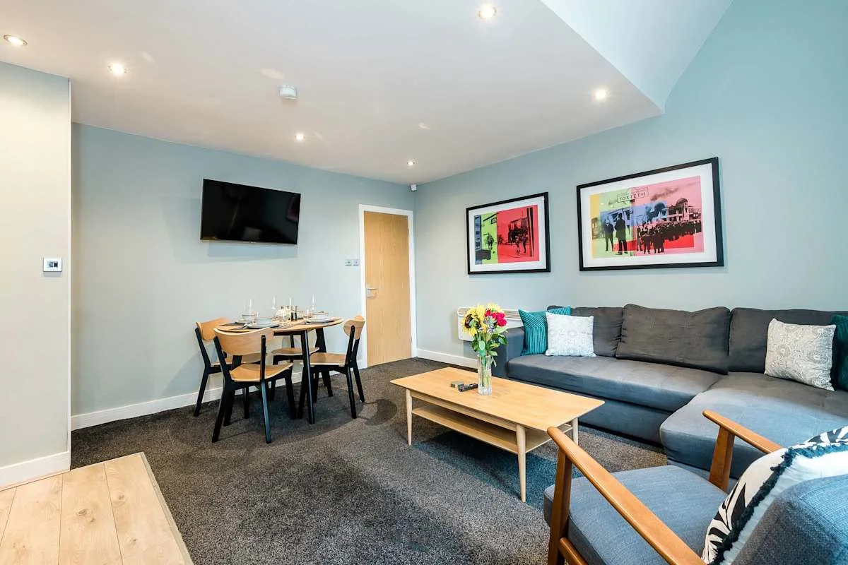 A living room with a dining table, seating, and colorful framed artwork.
