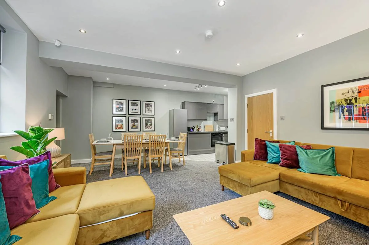 A living and dining area with seating, a dining table, and an open kitchen.