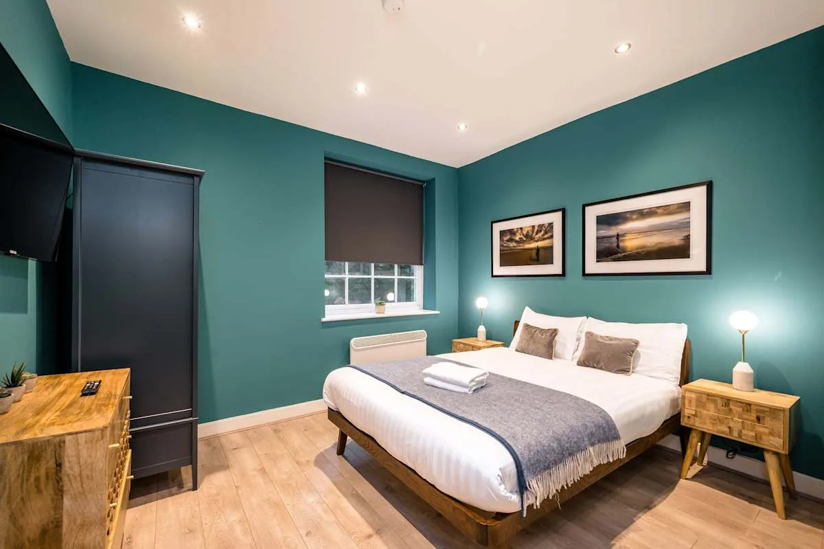 A bedroom with a neatly made bed and framed pictures on the wall.