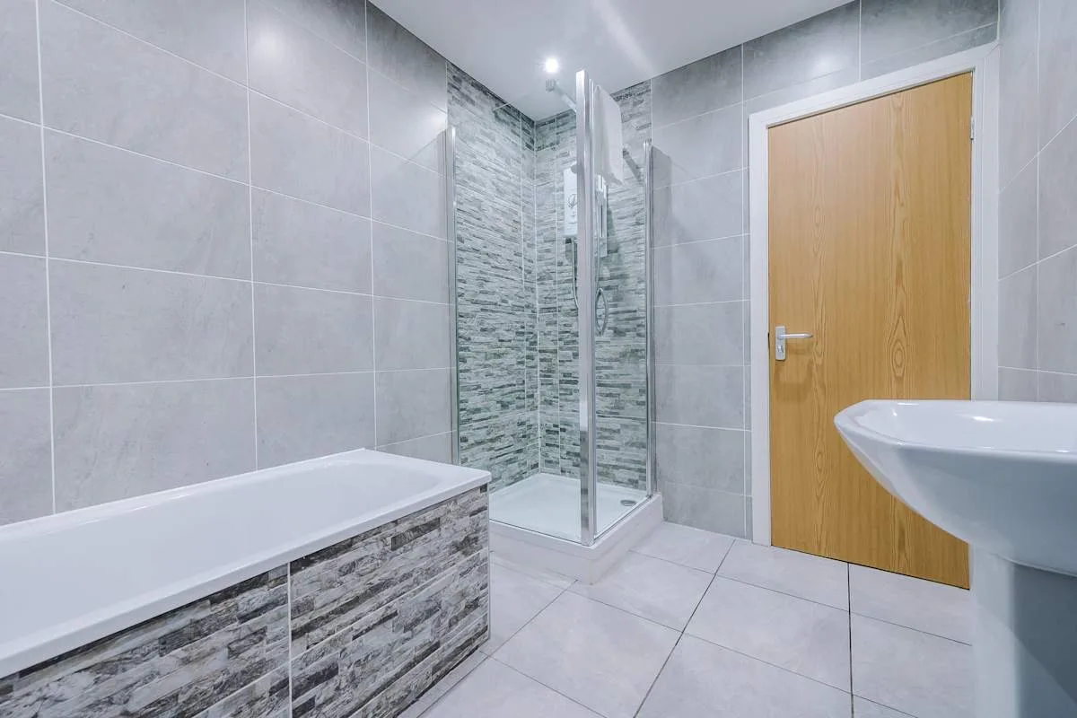 A tiled bathroom with a bathtub, shower, and wall-mounted sink.
