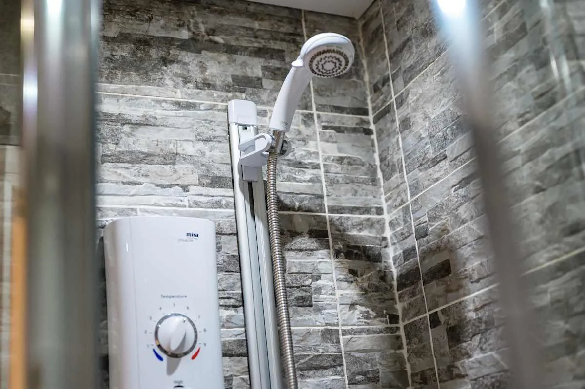 A shower with a handheld showerhead and wall-mounted water heater.