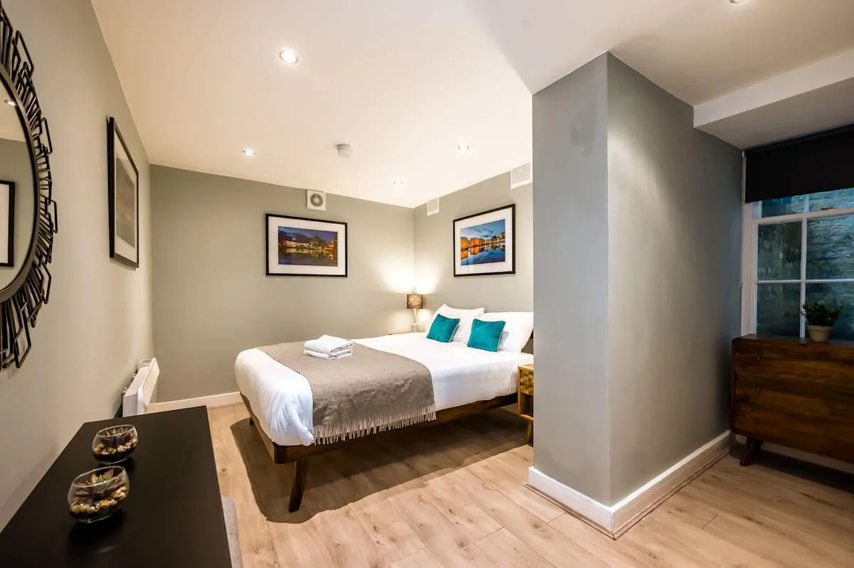 A bedroom with a neatly made bed and framed artwork on the walls.