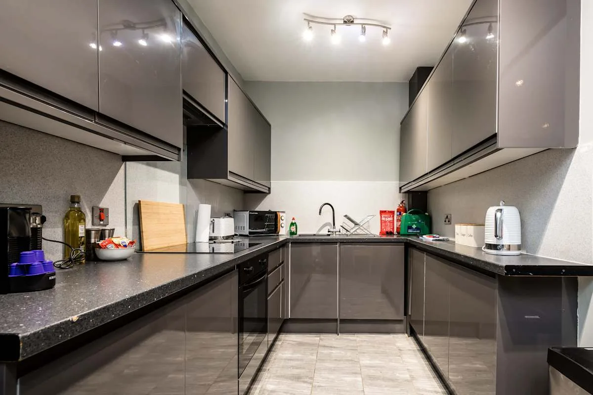 A modern kitchen with dark cabinetry and countertops along two walls.