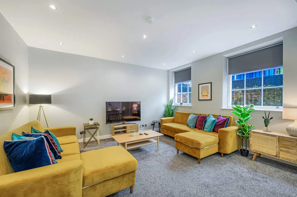 A bright living room with yellow seating arranged around a coffee table.