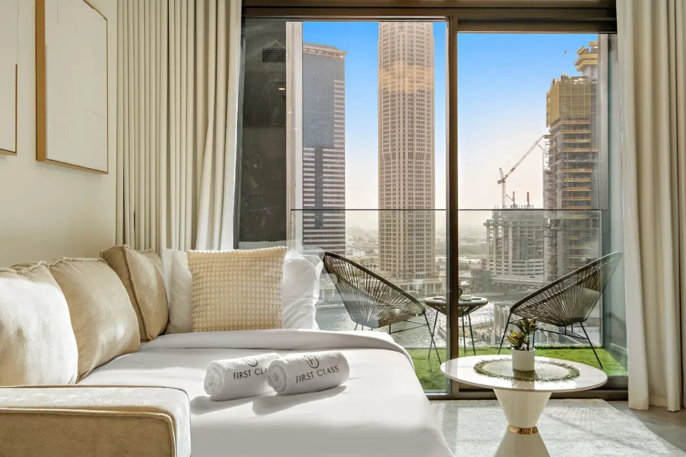 Una luminosa sala de estar con una cama junto a ventanales con vistas a edificios de la ciudad.