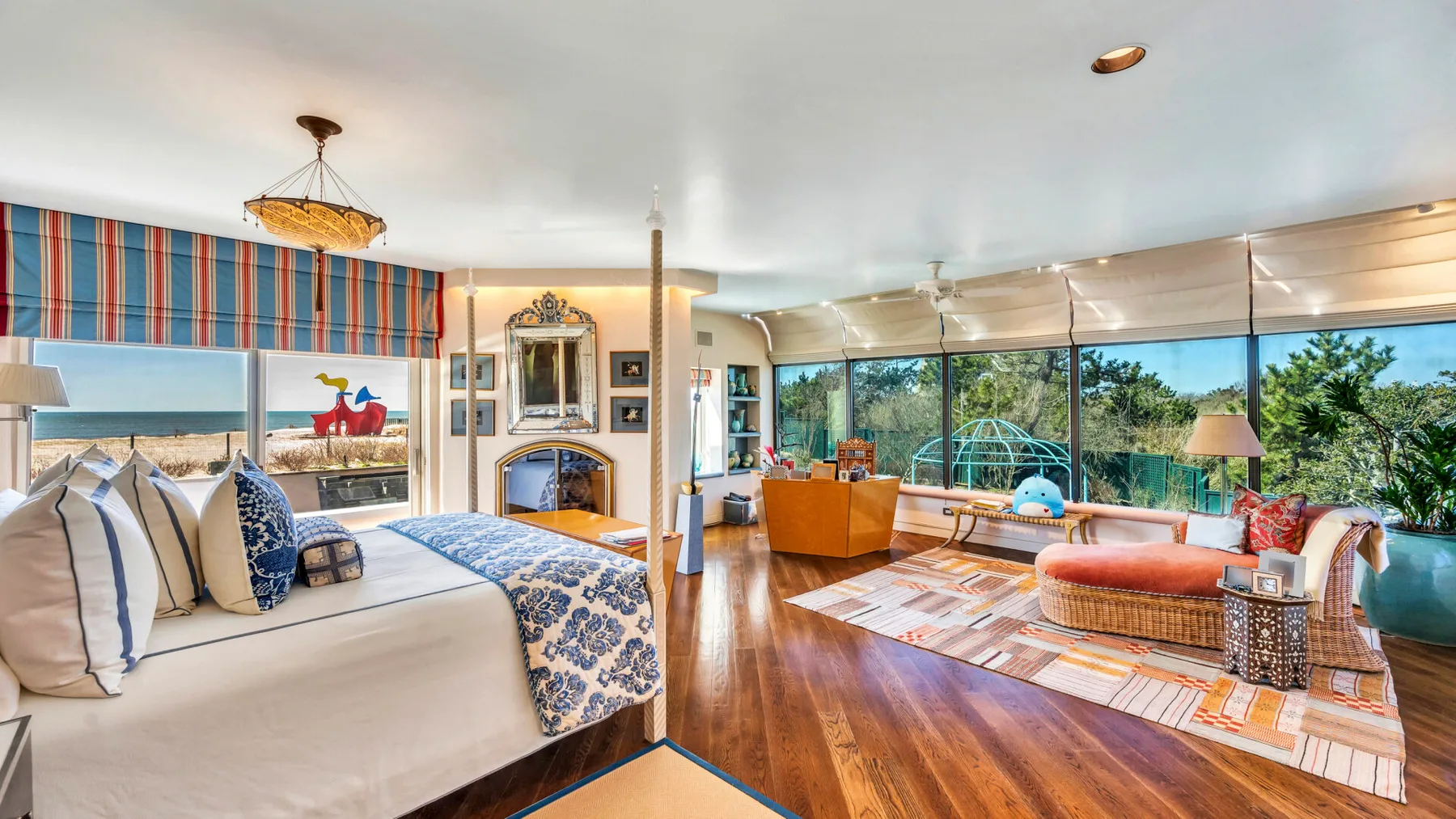 A bright bedroom opens onto a sitting area with wide windows and a garden view.