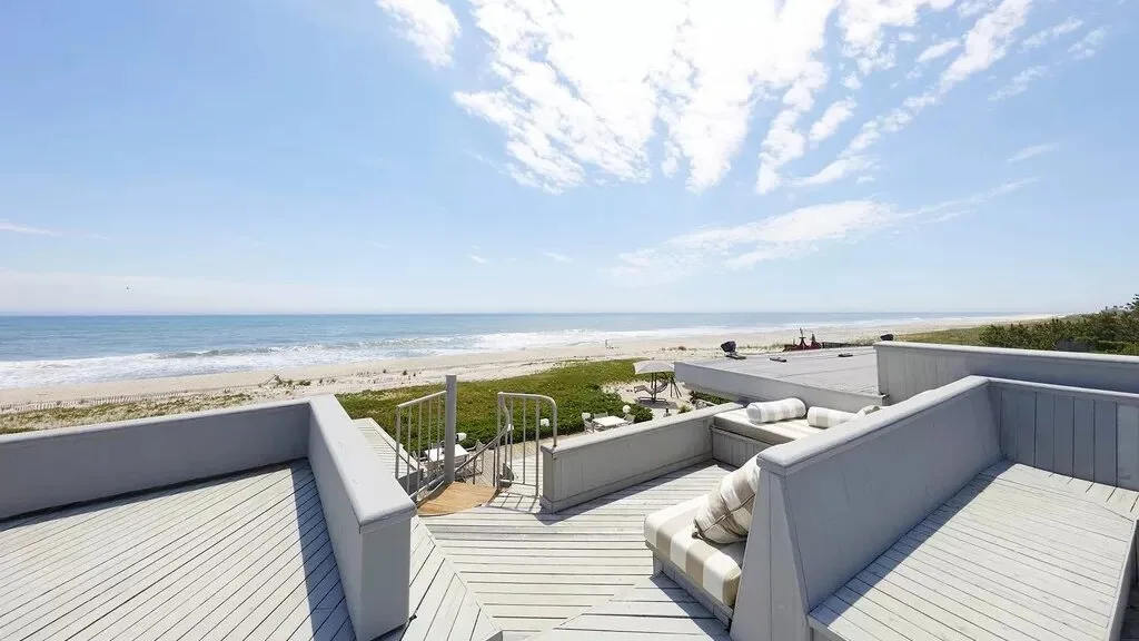 A beachfront terrace has built-in seating and a view of the ocean.