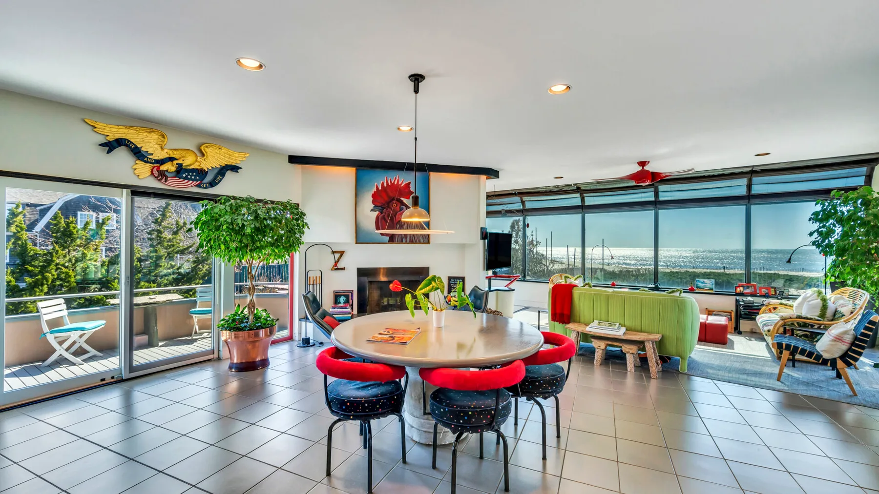 A bright living and dining area has a round table and wide windows overlooking the water.