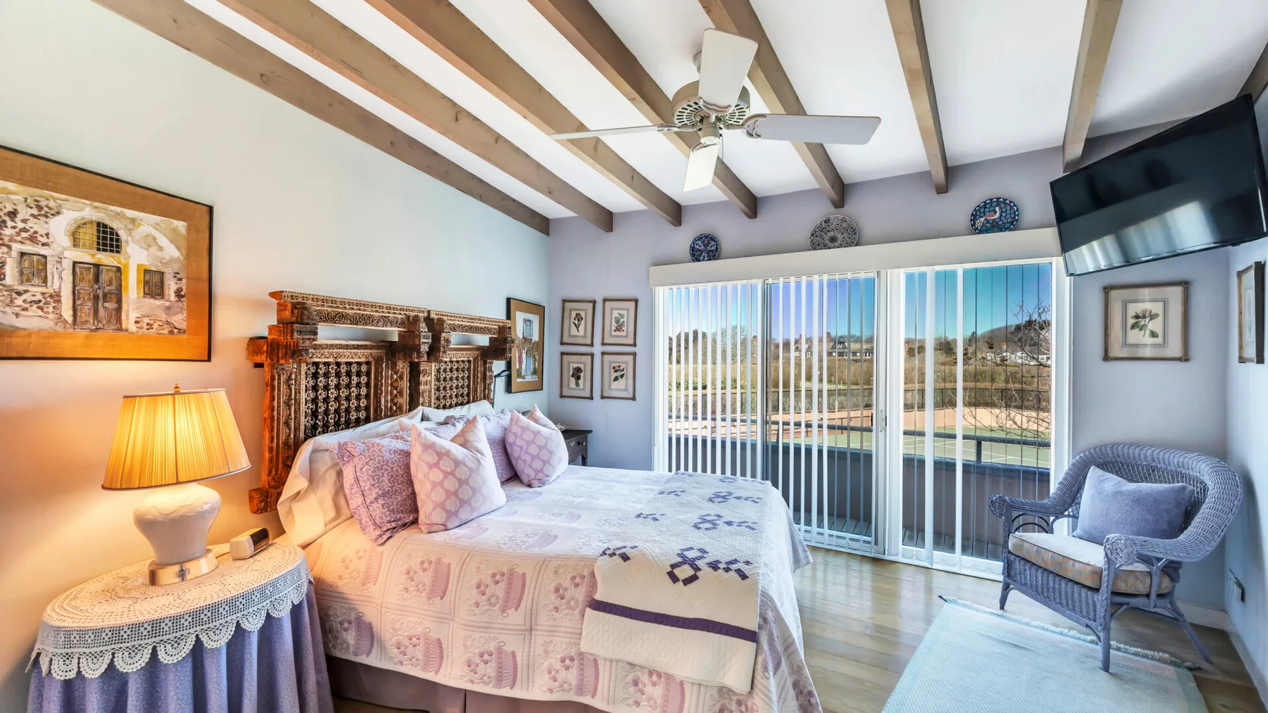 A bedroom with a bed, sliding glass doors, and a chair.