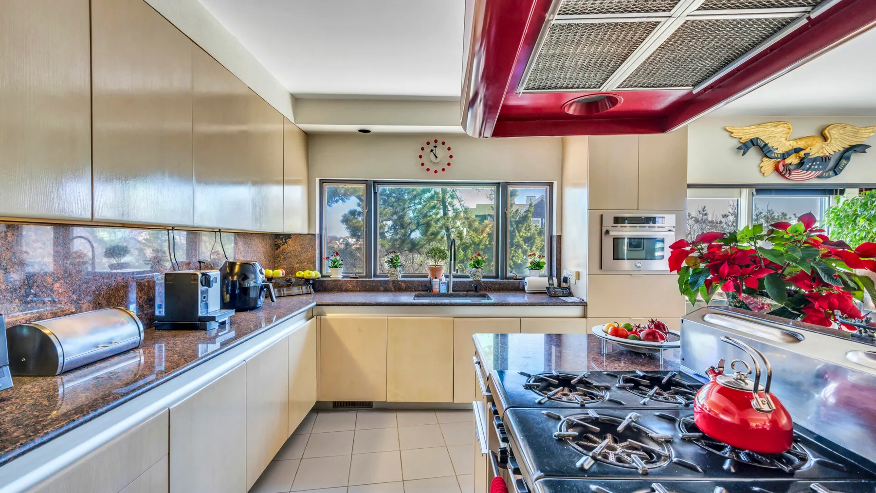 A spacious kitchen with a central cooking island and windows overlooking greenery.