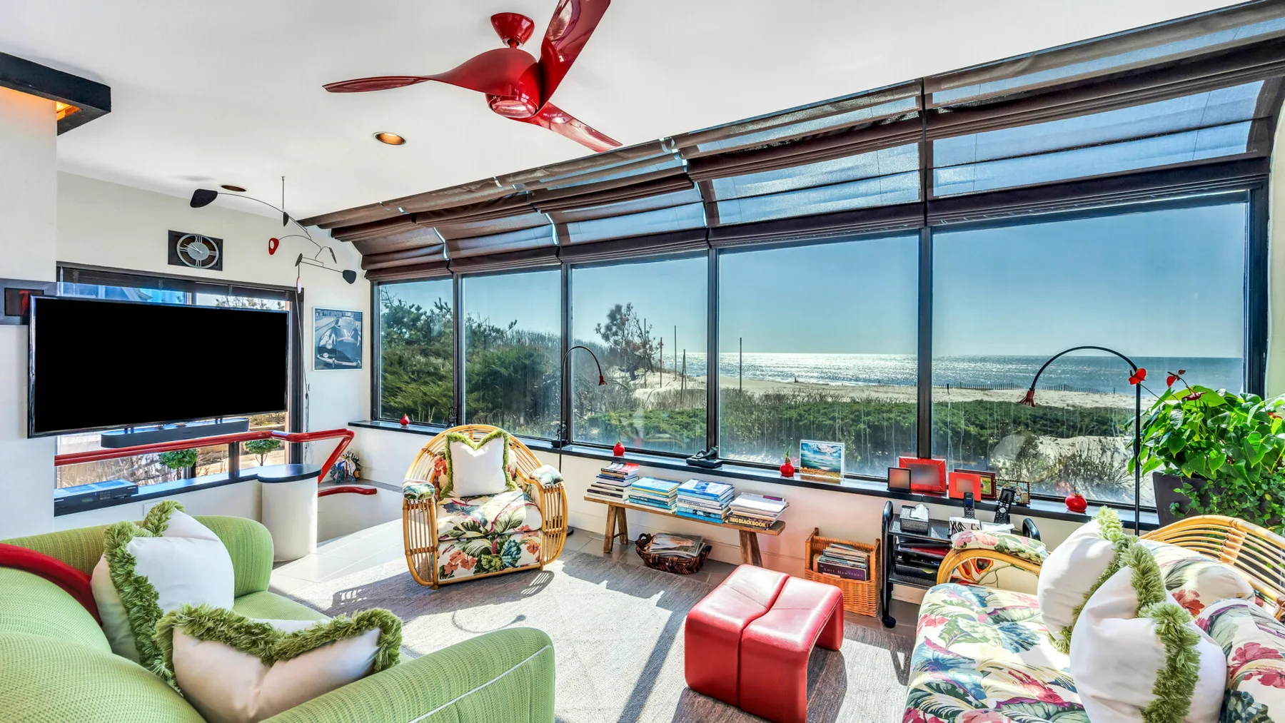 A bright lounge has large windows overlooking the ocean and seating around a low table.