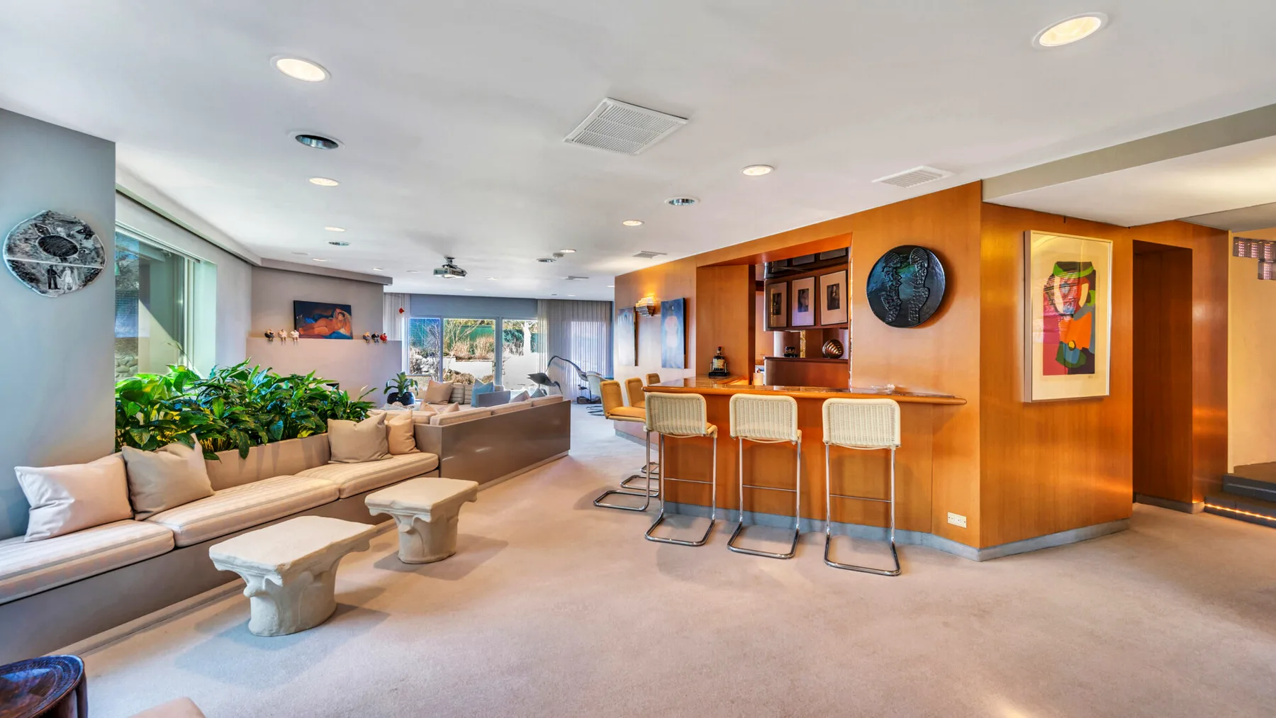 A spacious lounge with seating, a bar counter, and large windows.