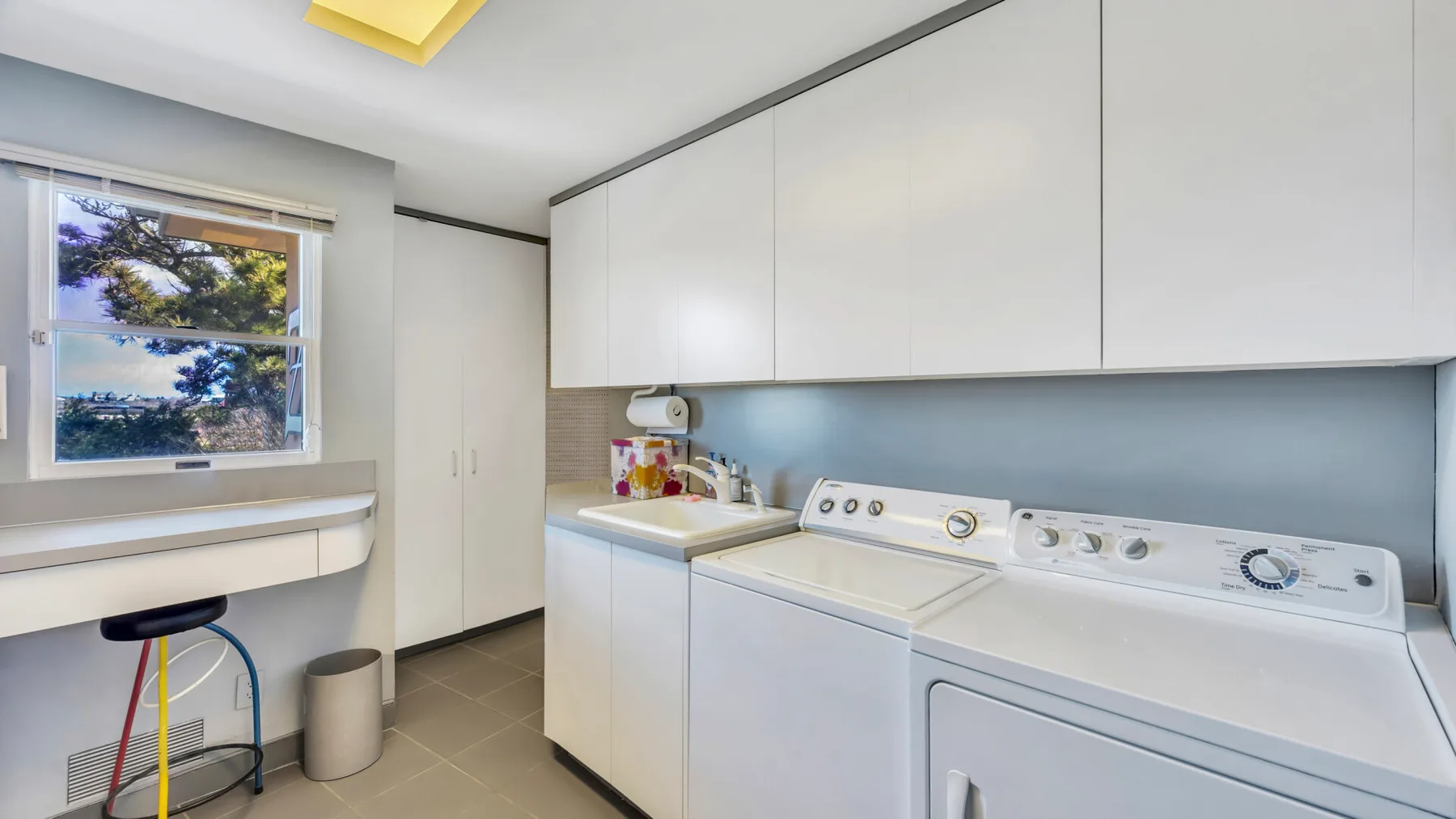 A laundry room with a washer and dryer beneath white cabinets.