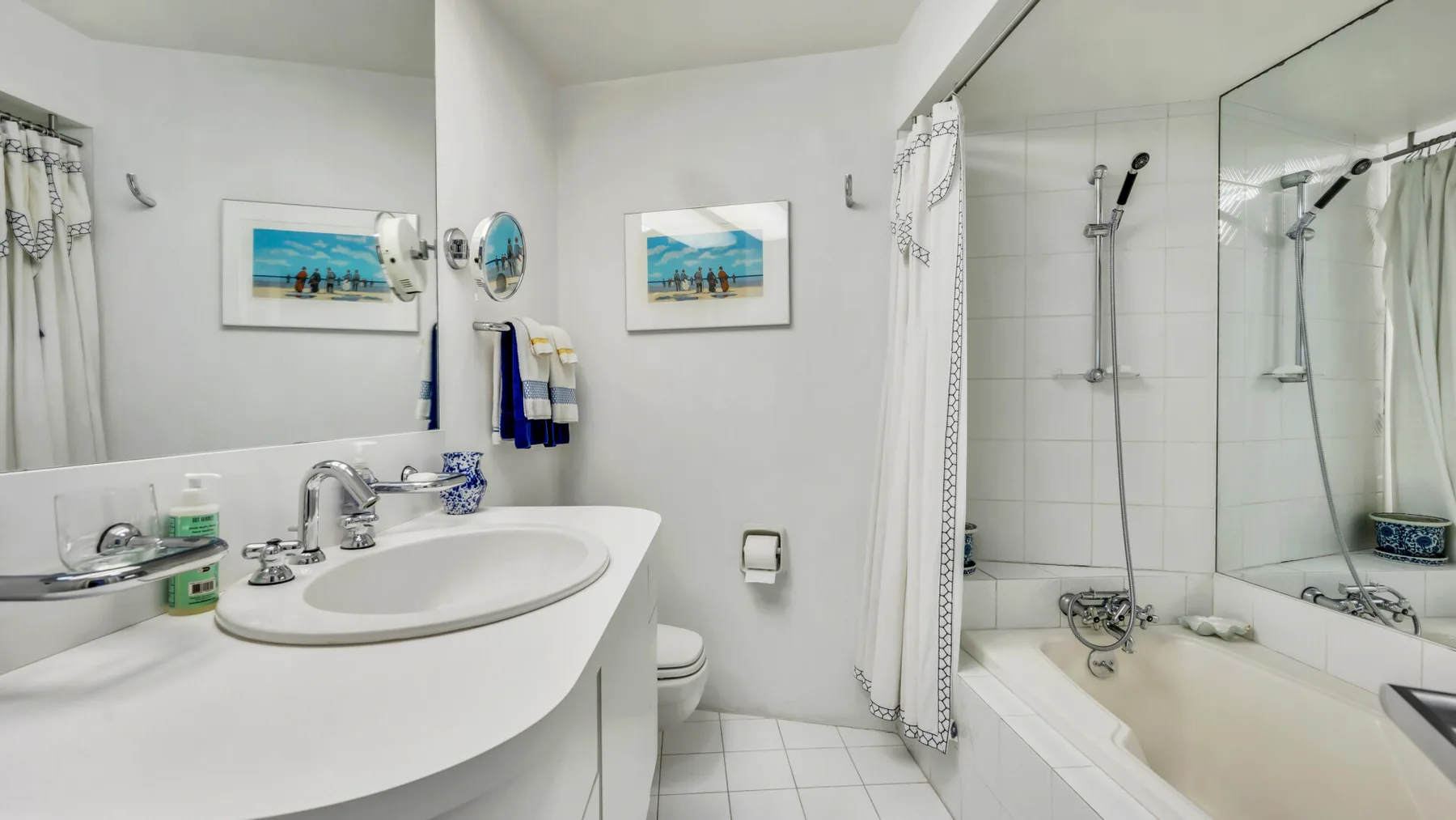 A bright bathroom with a sink, mirror, and shower.