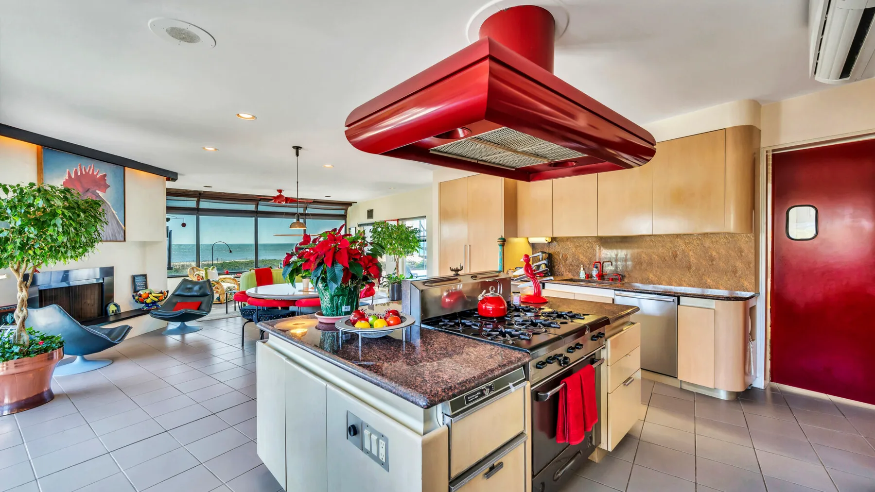 An open kitchen with a central island and red range hood.