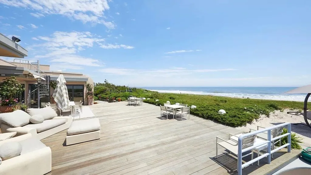 A spacious seaside deck with outdoor seating overlooks the ocean.