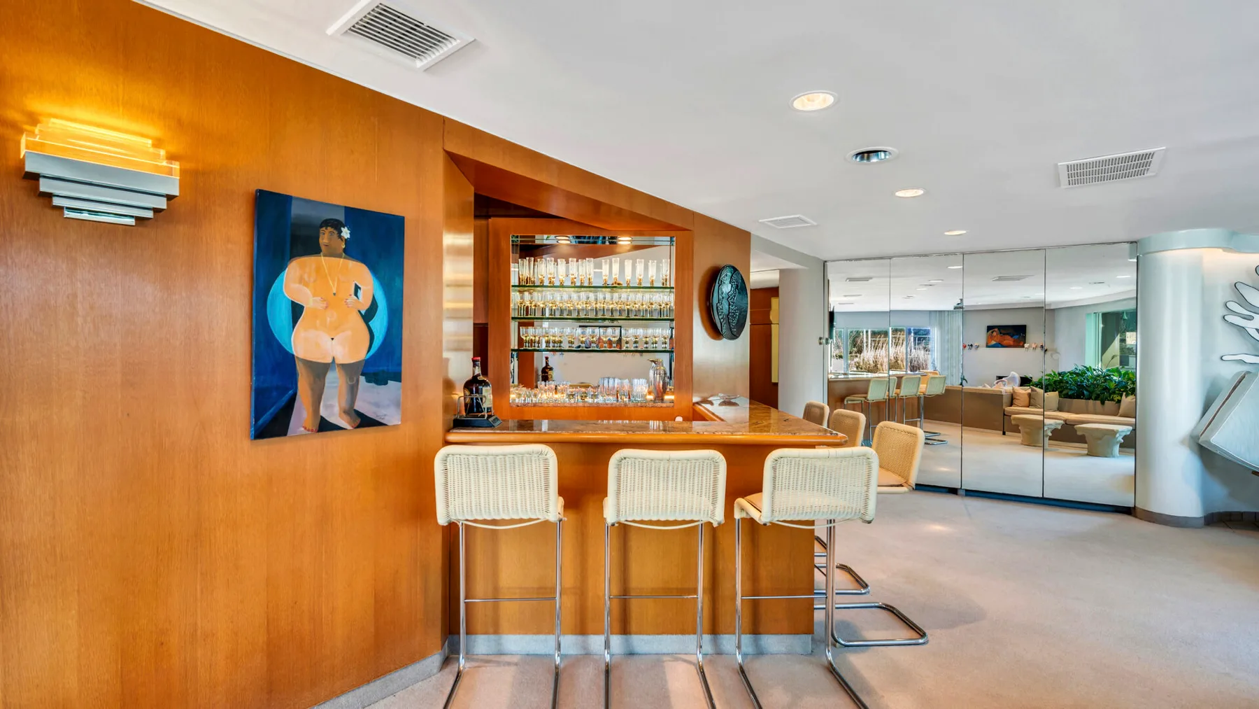 A bar area with stools and a mirrored lounge behind it.